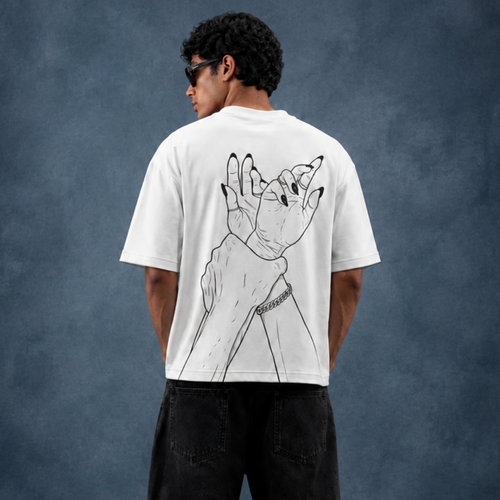 A man stands with his back to the camera wearing a white graphic t-shirt with a black line art illustration of a hand holding a wolf head, paired with black jeans, against a textured dark blue studio backdrop.