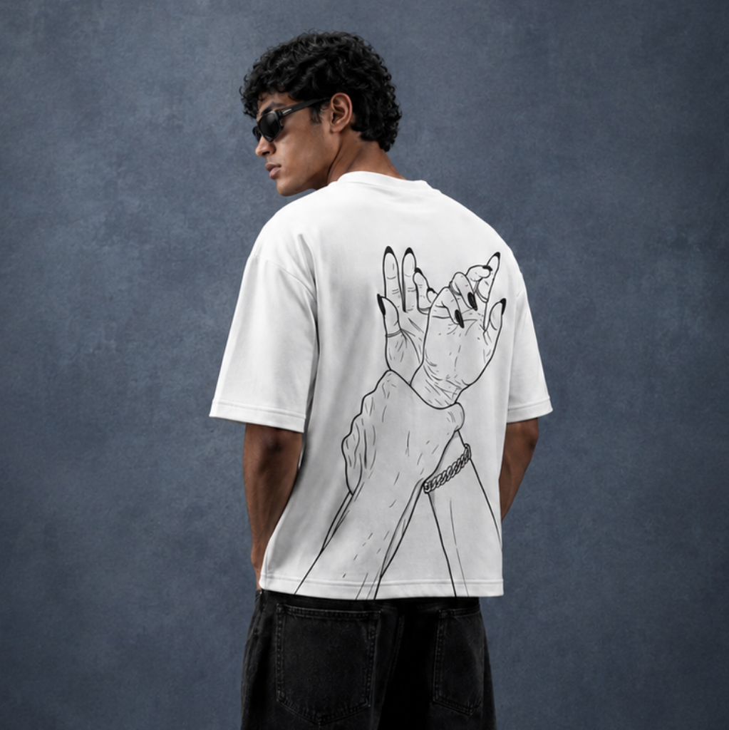 A man wearing a white graphic t-shirt with a black line art illustration on the back, paired with black jeans and sunglasses, standing against a dark textured studio backdrop.