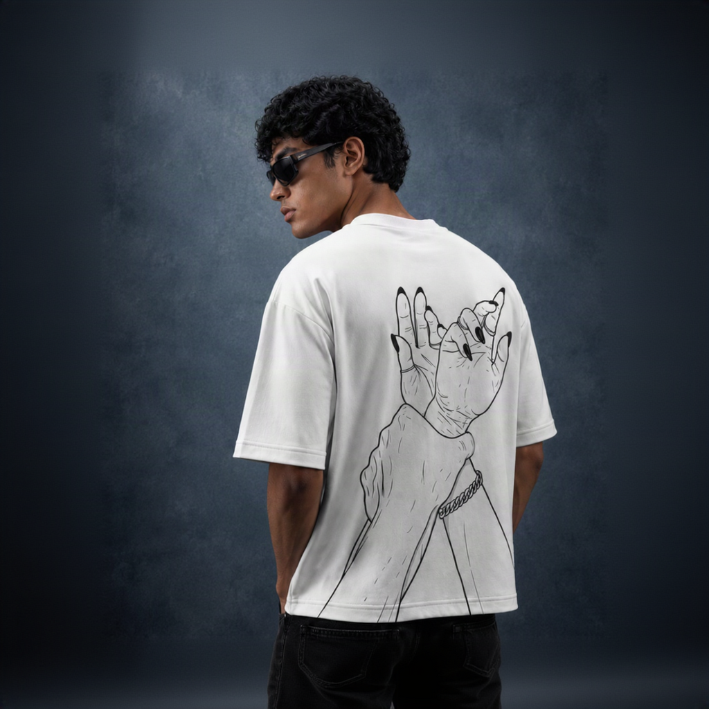 A man wearing a white t-shirt with a black line art graphic of a hand with long nails on the back, photographed from behind against a dark textured studio background.